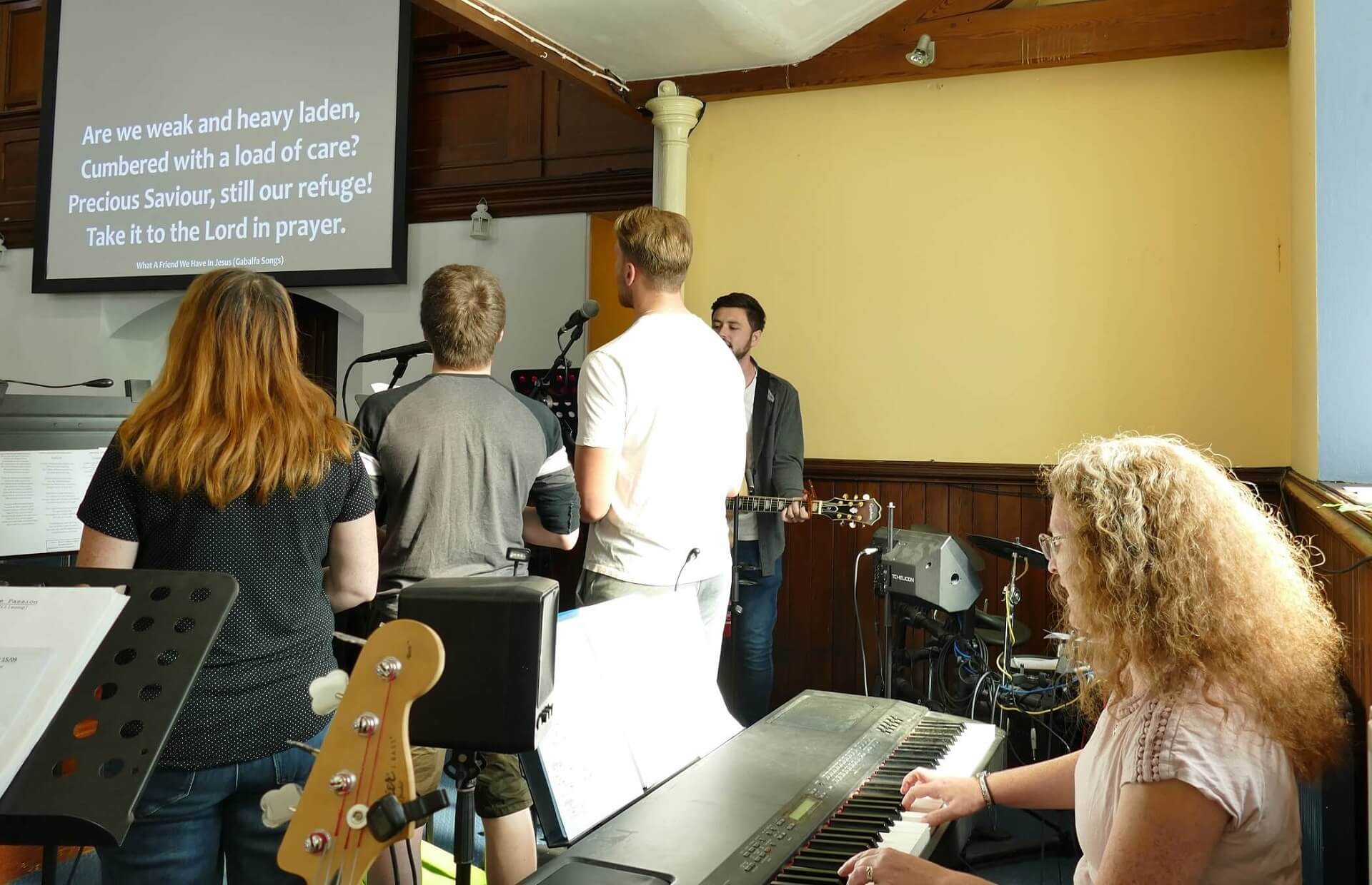 People singing in front of Lady Playing Keyboard